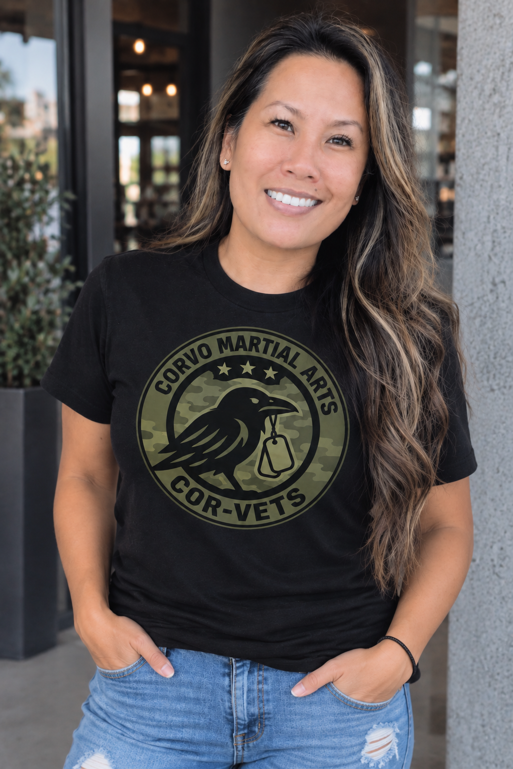 Woman wearing the black Corvo Martial Arts Cor-Vets shirt with camouflage crow logo, created by SKiP Design Co.